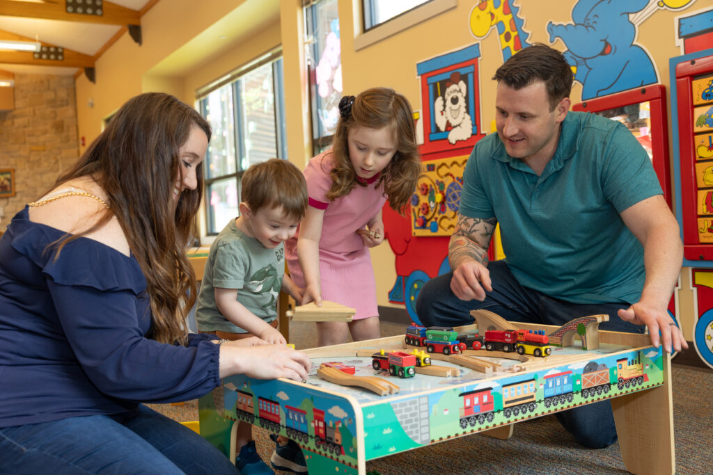 Family gathering around a toy train table playing together